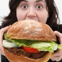 Super huge giant burger and teen girl trying to eat it.